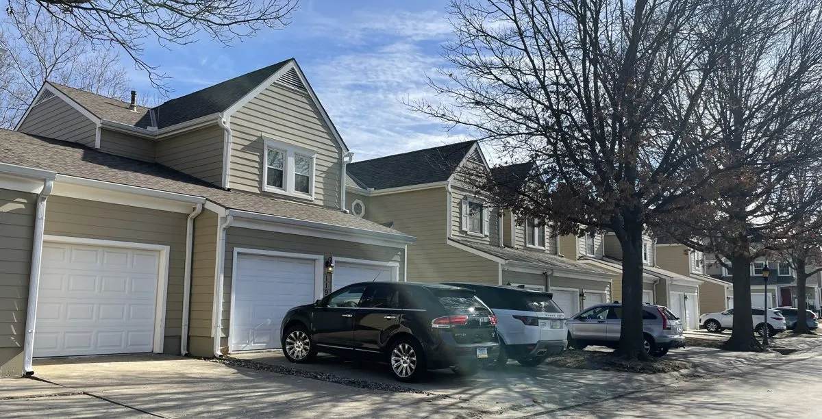 Row of attached two-story townhomes with shared shingle roofs