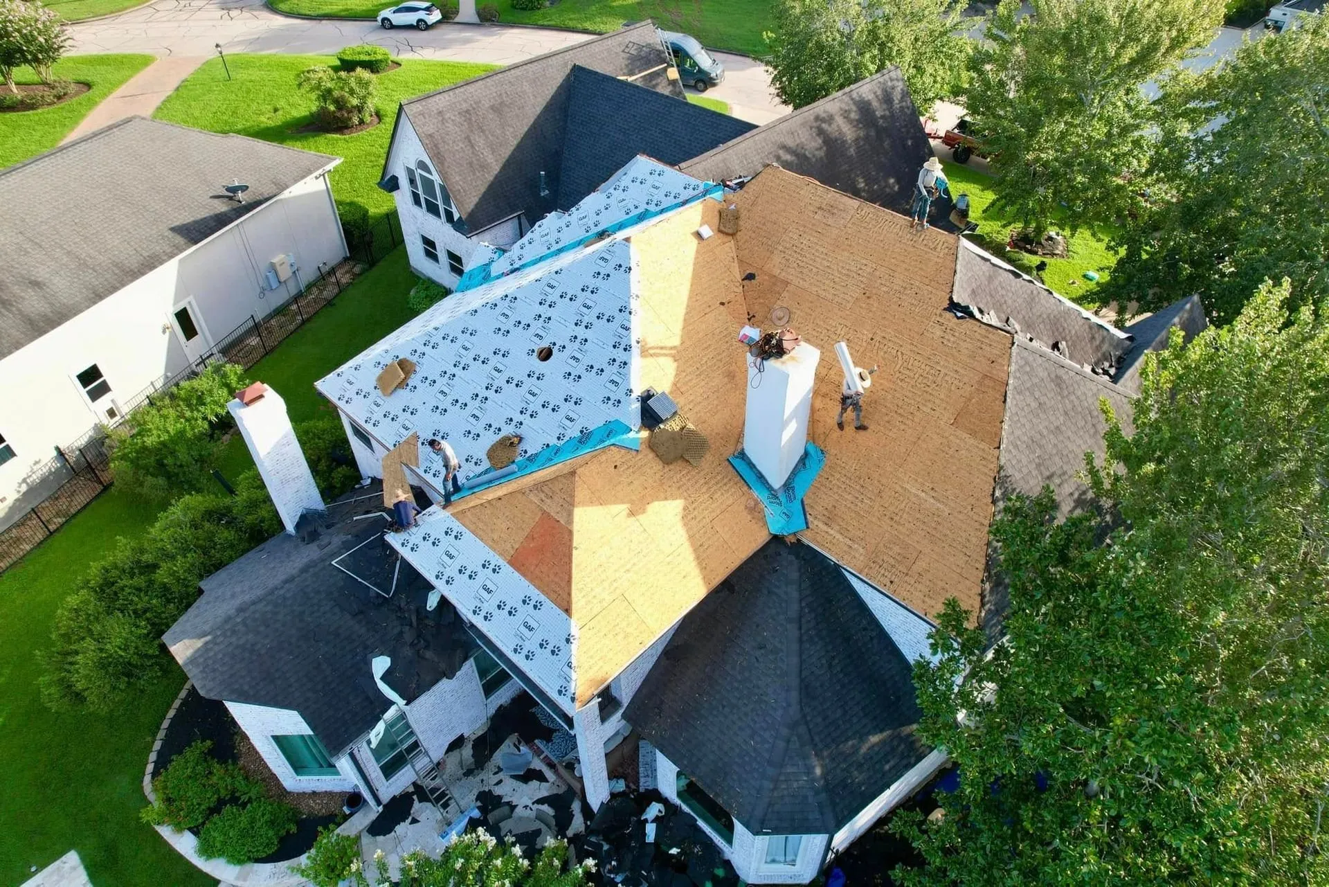 Aerial view of a roof mid-replacement with new underlayment and decking